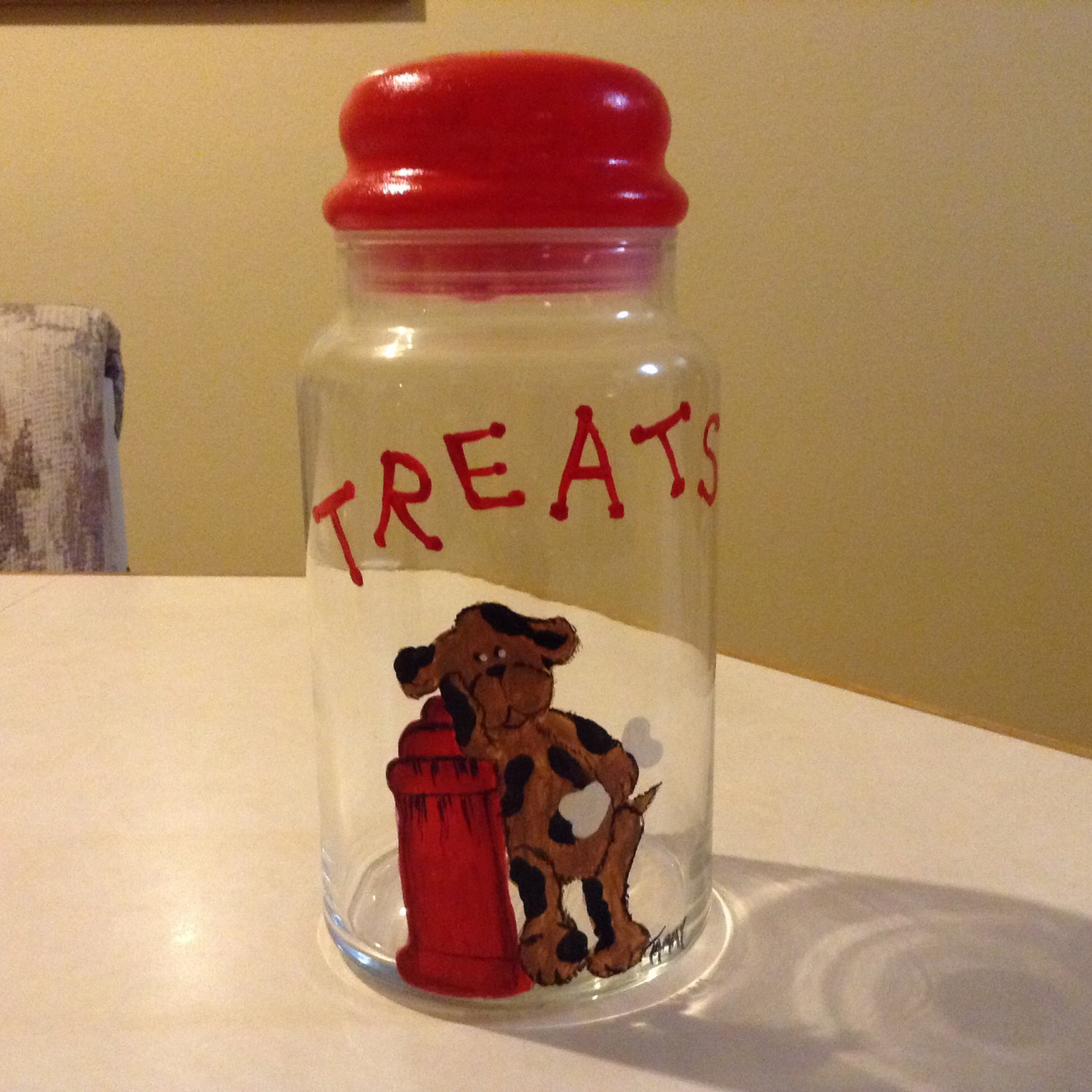 Dog treat jar with cute cartoon doggie leaning on a fire hydrant, hand